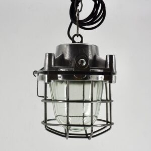 Suspension industrielle ADF vintage avec grille de protection carrée en métal et globe en verre transparent.